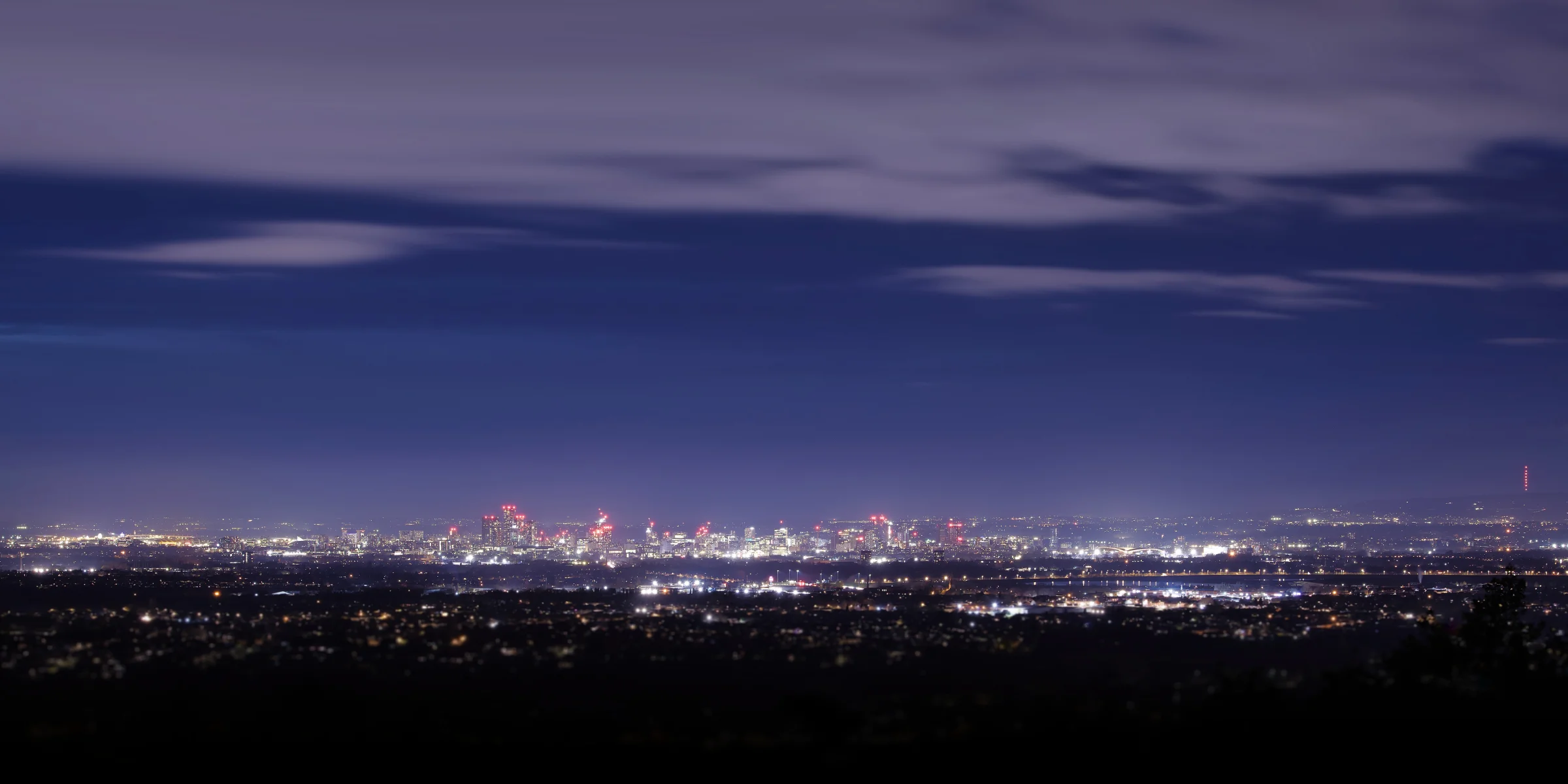 There's a strong chance this image contains the following subjects: light,  water,  landscape,  sea,  moon,  evening,  dusk,  salford,  manchester,  greatermanchester,  skyline. The photographer has provided the following description: A super-wide shot of a cityscape. This shows Salford far left, with Manchester City Centre in the centre of the image and East Manchester / Etihad Stadium to the right. Taken from 8 miles away in Cheshire! This is a ten shot panoramic image. Photographer_name: Chris Michael. Title: The Manchester Skyline. The photographer has provided the following description: A super-wide shot of a cityscape. This shows Salford far left, with Manchester City Centre in the centre of the image and East Manchester / Etihad Stadium to the right. Taken from 8 miles away in Cheshire! This is a ten shot panoramic image. Make: canon. Model: EOS R. Technical: 70-200mm. Published: 2025-09-10 13:49:32