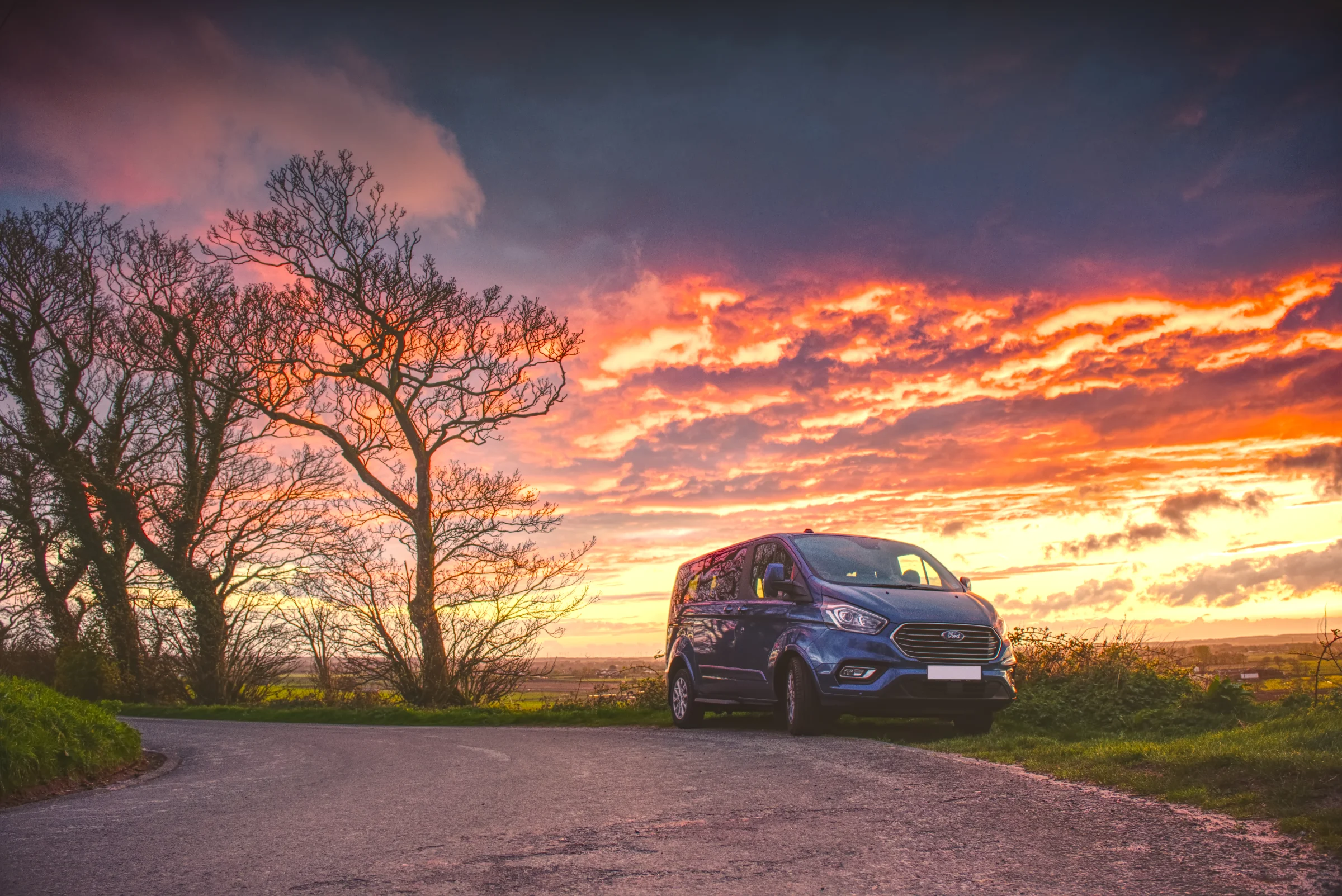 There's a strong chance this image contains the following subjects: tree,  landscape,  sunset,  road. The photographer has provided the following description: I just had to pull over and grab this shot. Taken in Ormskirk, Lancashire during sunset. Photographer_name: Chris Michael. Title: Sky on Fire. The photographer has provided the following description: I just had to pull over and grab this shot. Taken in Ormskirk, Lancashire during sunset. Make: canon. Model: EOS R. Technical: 16mm. Published: 2025-09-07 22:06:49