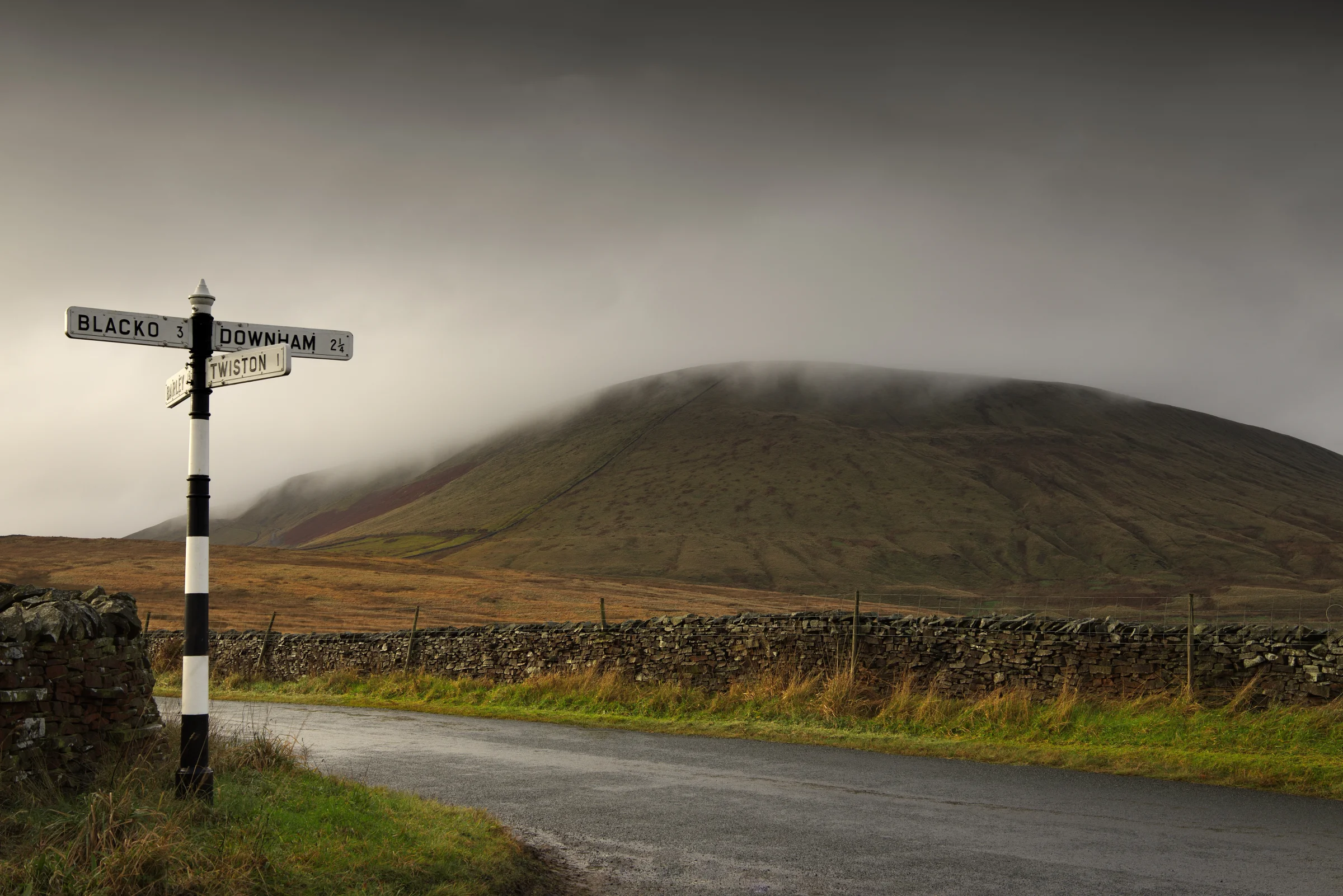 There's a strong chance this image contains the following subjects: landscape,  travel,  road,  lancashire,  pendlehill. The photographer has provided the following description: Here is Pendle Hill seen from Twiston in Lancashire during a foggy morning. Photographer_name: Chris Michael. Title: Pendle Hill. The photographer has provided the following description: Here is Pendle Hill seen from Twiston in Lancashire during a foggy morning. Make: canon. Model: EOS R. Technical: RF16mm. Published: 2025-09-06 19:14:01