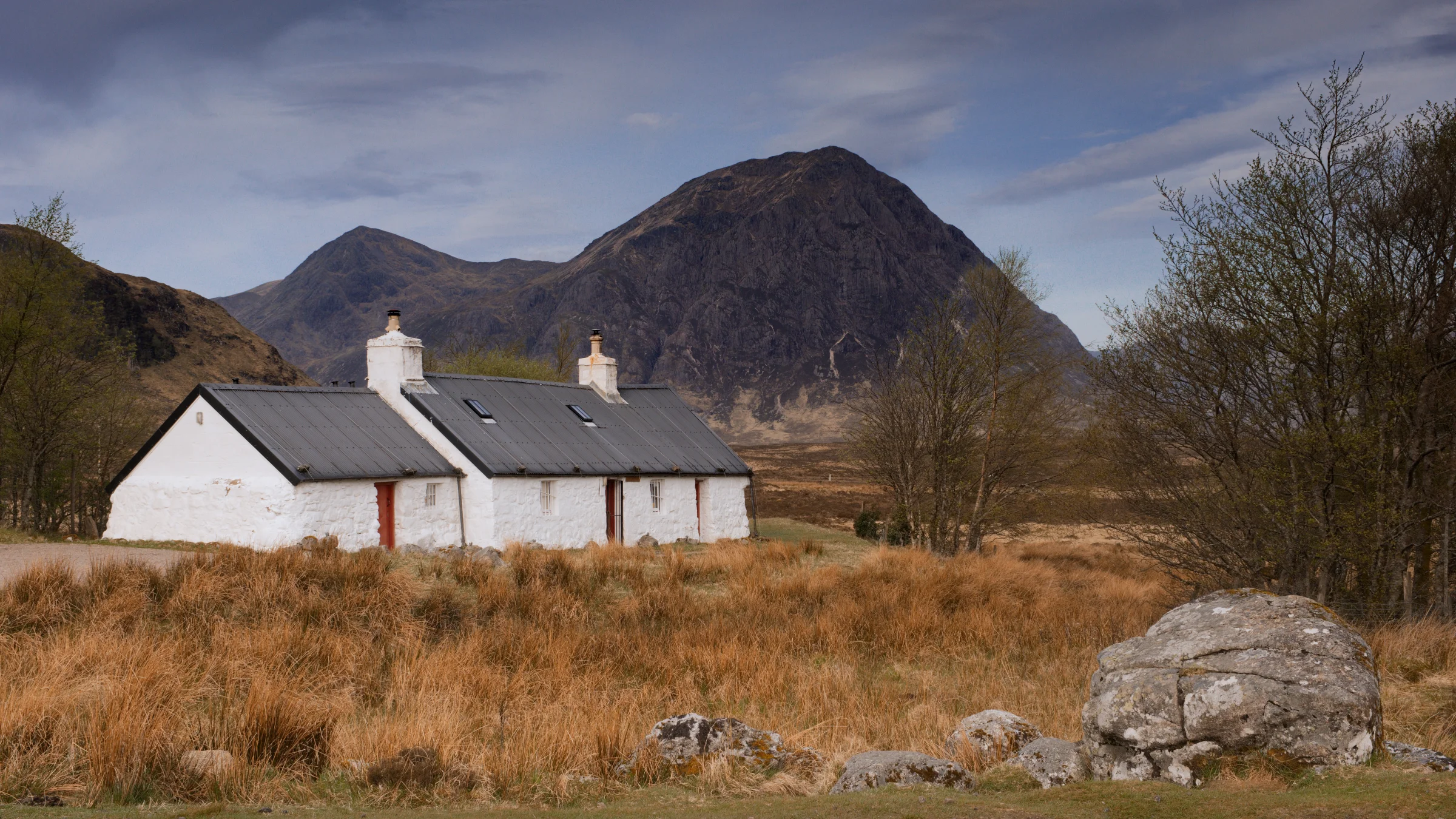 There's a strong chance this image contains the following subjects: house,  sky,  landscape,  nature,  farm,  scotland,  highlands,  scottishhighlands,  buachailleetivemor,  glencoe. The photographer has provided the following description: Blackrock Cottage in Glencoe, seen with Buachaille Etive Mor in the distance! Taken April 2025. Photographer_name: Chris Michael. Title: Blackrock Cottage. The photographer has provided the following description: Blackrock Cottage in Glencoe, seen with Buachaille Etive Mor in the distance! Taken April 2025. Make: fujifilm. Model: X-T5. Technical: 16-80mm. Published: 2025-09-08 18:43:18
