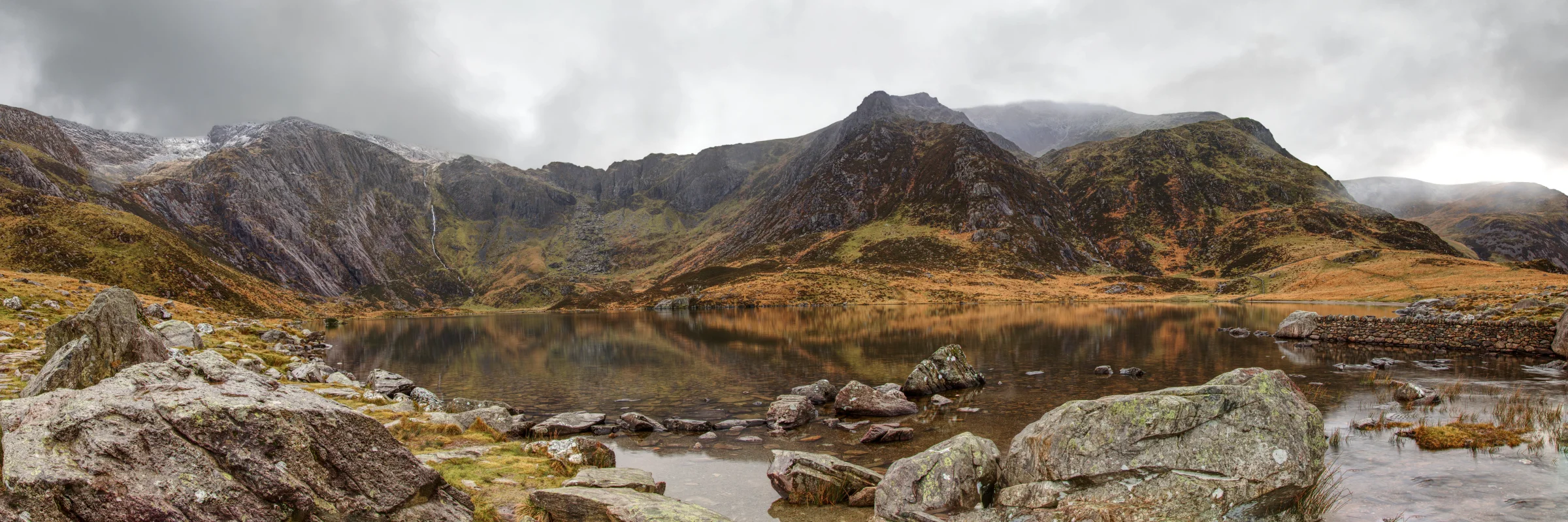 There's a strong chance this image contains the following subjects: sky,  water,  landscape,  lake,  travel,  rock,  nature,  river,  reflection,  wales,  snowdonia,  eryri,  eryrinationalpark,  nationalpark,  snowdon. The photographer has provided the following description: An 8 shot panoramic photo of Cwm Idwal in Snowdonia. Photographer_name: Chris Michael. Title: Cwm Idwal. The photographer has provided the following description: An 8 shot panoramic photo of Cwm Idwal in Snowdonia. Make: canon. Model: EOS R. Technical: 16mm. Published: 2025-09-09 14:24:10