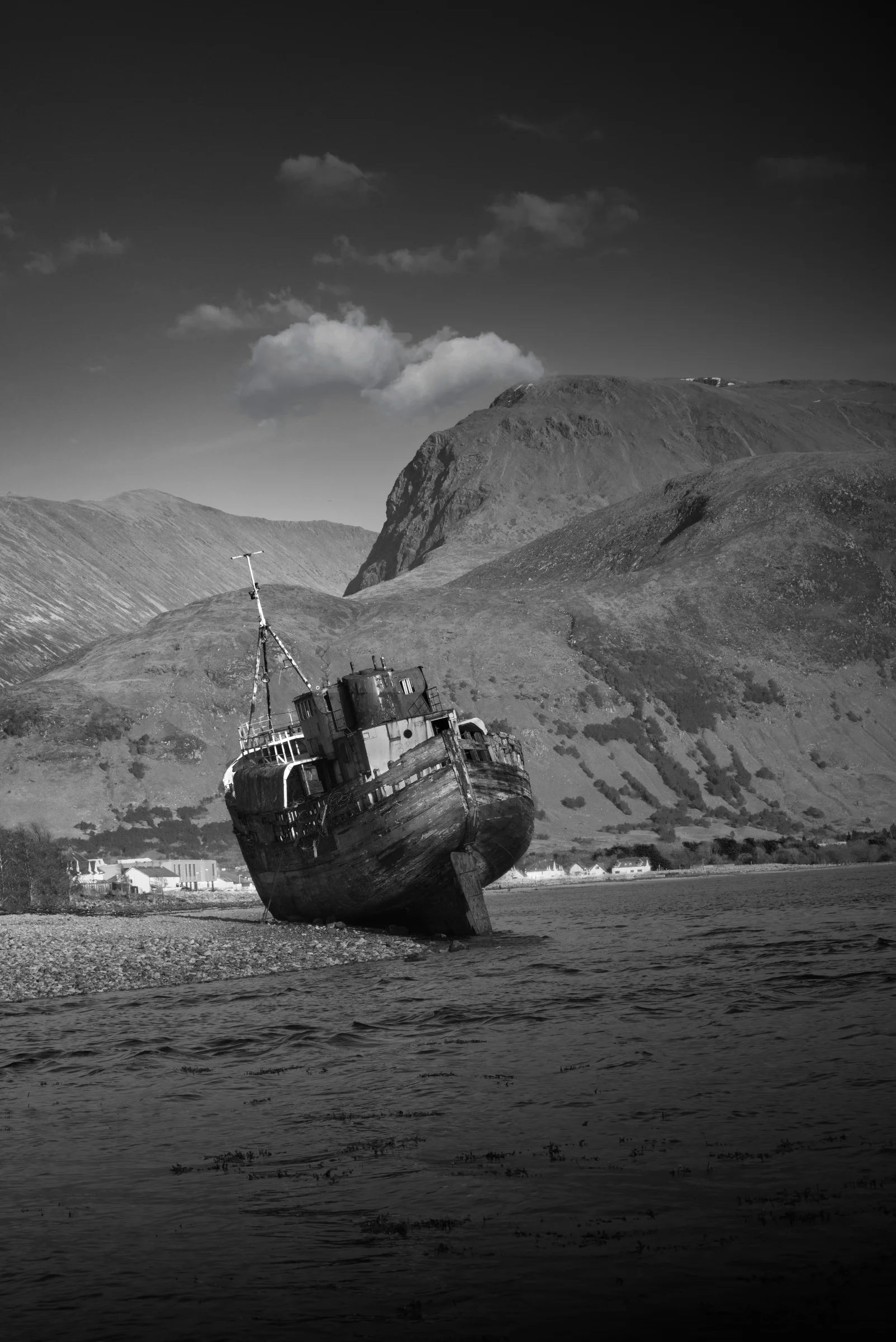 There's a strong chance this image contains the following subjects: monochrome,  water,  landscape,  sea,  beach,  ocean,  scotland,  scottishhighlands,  corpach,  fortwilliam,  bennevis,  seashore,  blackandwhite. The photographer has provided the following description: I don't often 'dabble' with black and white photography, but this photo made me realise I should do it more often. The beautiful Corpach shipwreck seen here with Ben Nevis (the tallest mountain in Scotland) in the background. Photographer_name: Chris Michael. Title: The Corpach Shipwreck. The photographer has provided the following description: I don't often 'dabble' with black and white photography, but this photo made me realise I should do it more often. The beautiful Corpach shipwreck seen here with Ben Nevis (the tallest mountain in Scotland) in the background. Make: fujifilm. Model: X-t5. Technical: 55-200mm at 200mm. Published: 2025-09-08 18:39:54