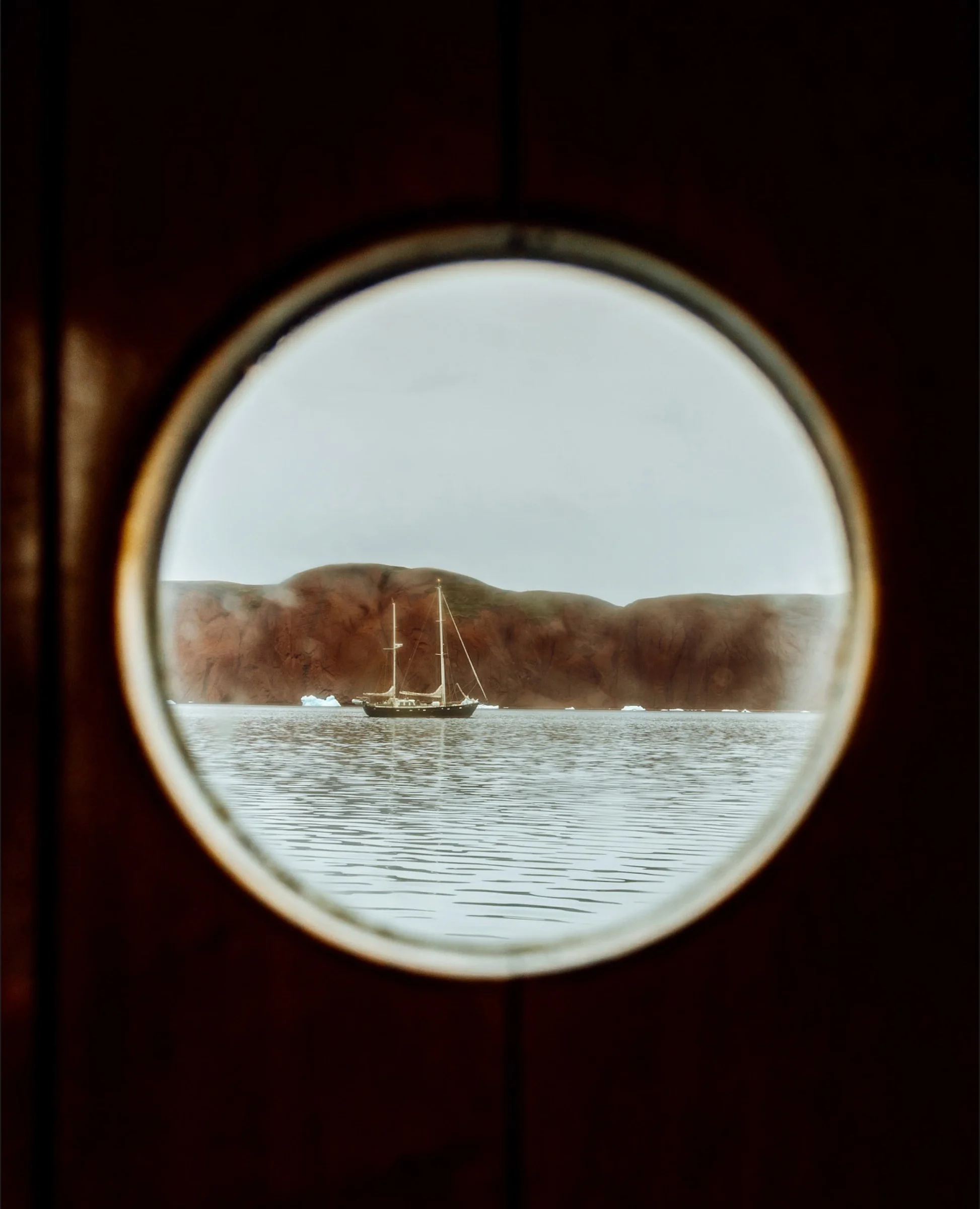 There's a strong chance this image contains the following subjects: travel,  ocean,  boat. The photographer has provided the following description: Nothing compares to the stories seen through a porthole, capturing life at sea. Source: https://www.instagram.com/heja_elsa/ Photographer_name: Elsa. Title: Window of nature. The photographer has provided the following description: Nothing compares to the stories seen through a porthole, capturing life at sea. Published: 2025-10-12 11:31:28