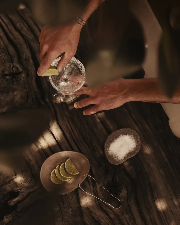 There's a strong chance this image contains the following subjects: people,  nature,  food. FOTO has this to say about the photograph: The gentle, delicate lighting, surrounded by a soft blur of out-of-focus leaves, naturally guides the viewer’s attention straight to the cocktail as it’s being carefully prepared. Source: https://www.instagram.com/ptrk.grf/ Photographer_name: Patrick Graf. Title: Shake, Serve and Savour. FOTO has this to say about the photograph: The gentle, delicate lighting, surrounded by a soft blur of out-of-focus leaves, naturally guides the viewer’s attention straight to the cocktail as it’s being carefully prepared. Published: 2025-06-23 17:34:47