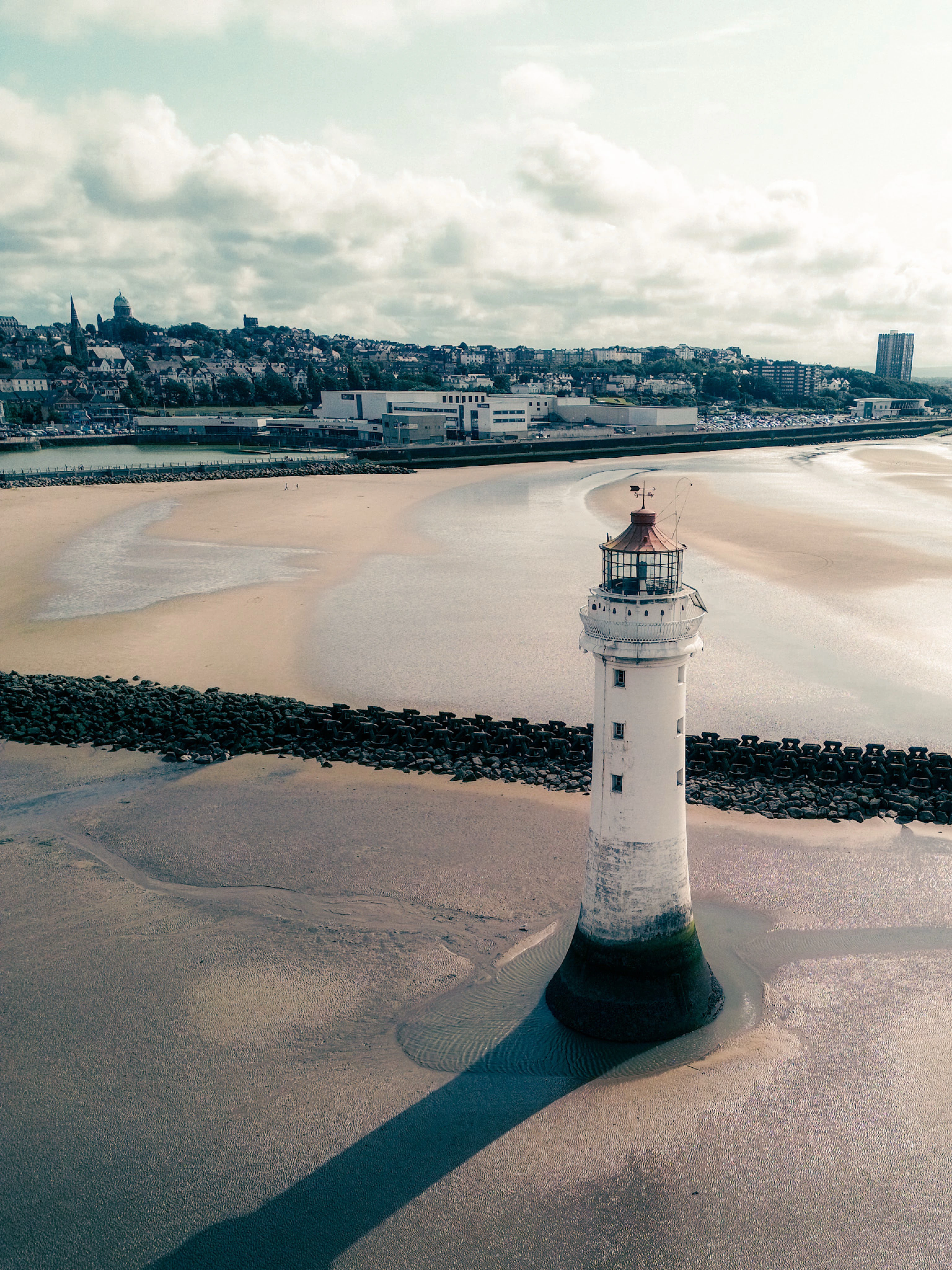 There's a strong chance this image contains the following subjects: water,  landscape,  travel,  sea,  beach,  lighthouse,  seashore,  aerial. The photographer has provided the following description: Taken with my DJI Mini 3, over the beaches in New Brighton. Perch Rock Lighthouse rises out of the shallows. Photographer_name: Lee Sillery. Title: Perch Rock Lighthouse. The photographer has provided the following description: Taken with my DJI Mini 3, over the beaches in New Brighton. Perch Rock Lighthouse rises out of the shallows. Make: dji. Model: Mini 3. Published: 2025-07-27 16:05:40